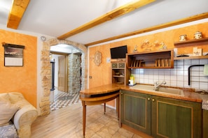 Una cocina con un arco de piedra, vigas de madera, un lavaplatos empotrado y un televisor.