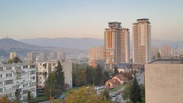 A cityscape with high-rise buildings, a clear sky, and a distant mountain range.