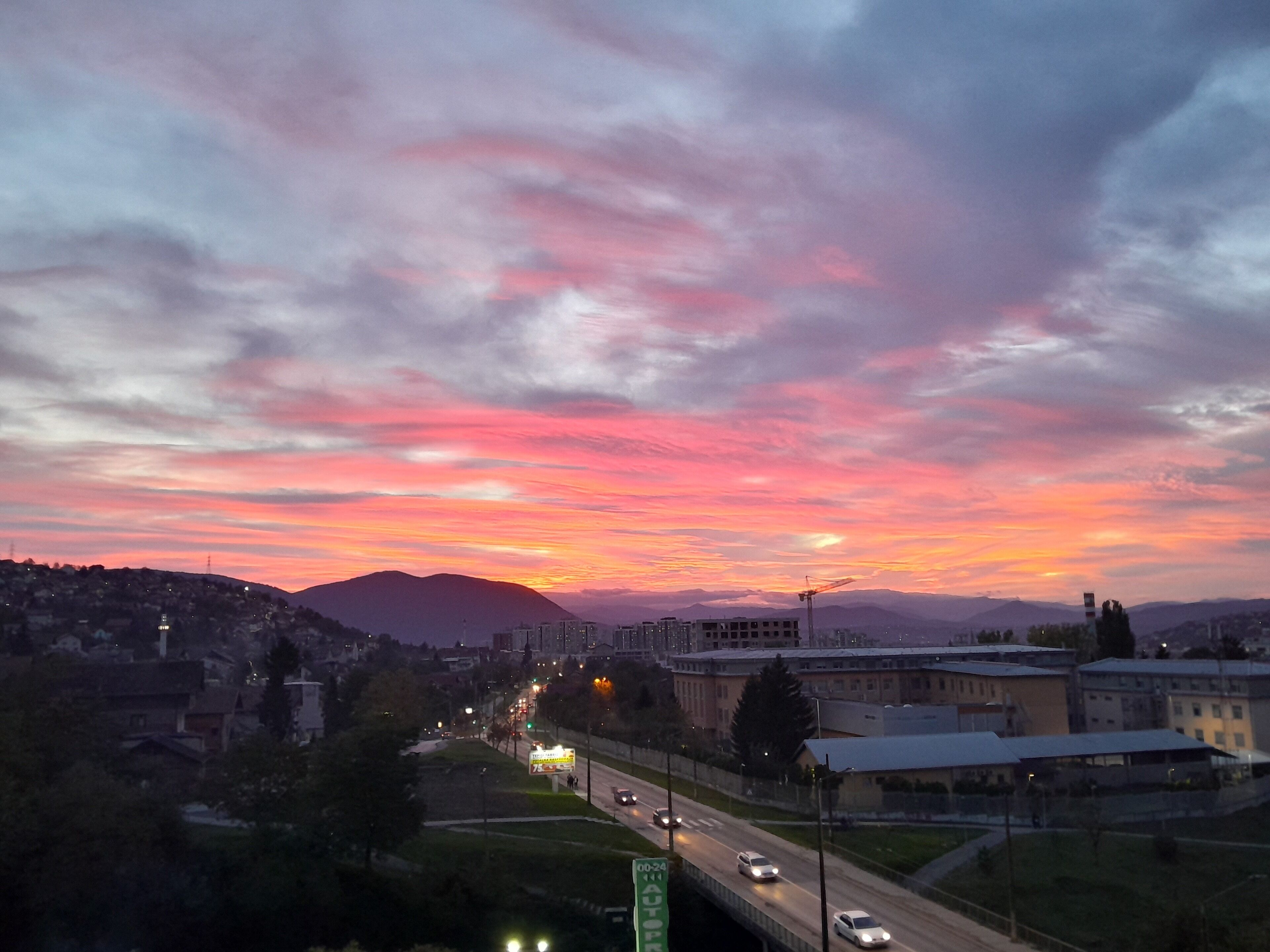 A cityscape with a sunset, a highway, and buildings.