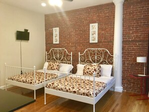 Una habitación con dos camas, un muro de ladrillo y un pilar blanco.