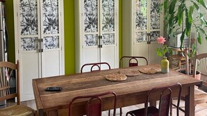 A dining area with a wooden table, red metal chairs, and a ceiling fan. - Charming house with swimming pool, garden, 8 min from Aix-en-Provence, near the Golf course (Aix-en-Provence)