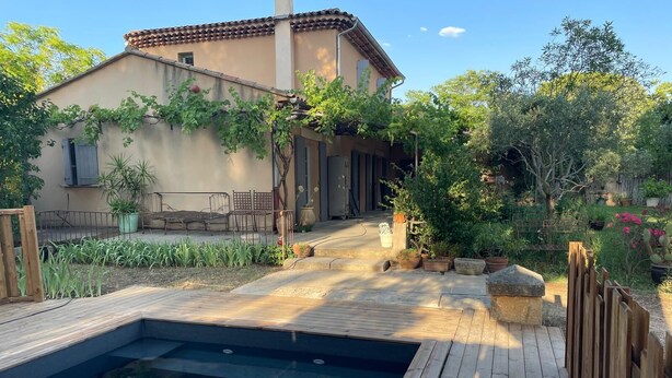 A swimming pool with a wooden deck, surrounded by a garden with various plants and a building with a tiled roof. - Charming house with swimming pool, garden, 8 min from Aix-en-Provence, near the Golf course (Aix-en-Provence)