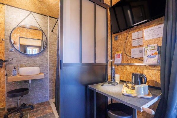 Een badkamer met een ronde spiegel, wastafel en handdoekhouder.