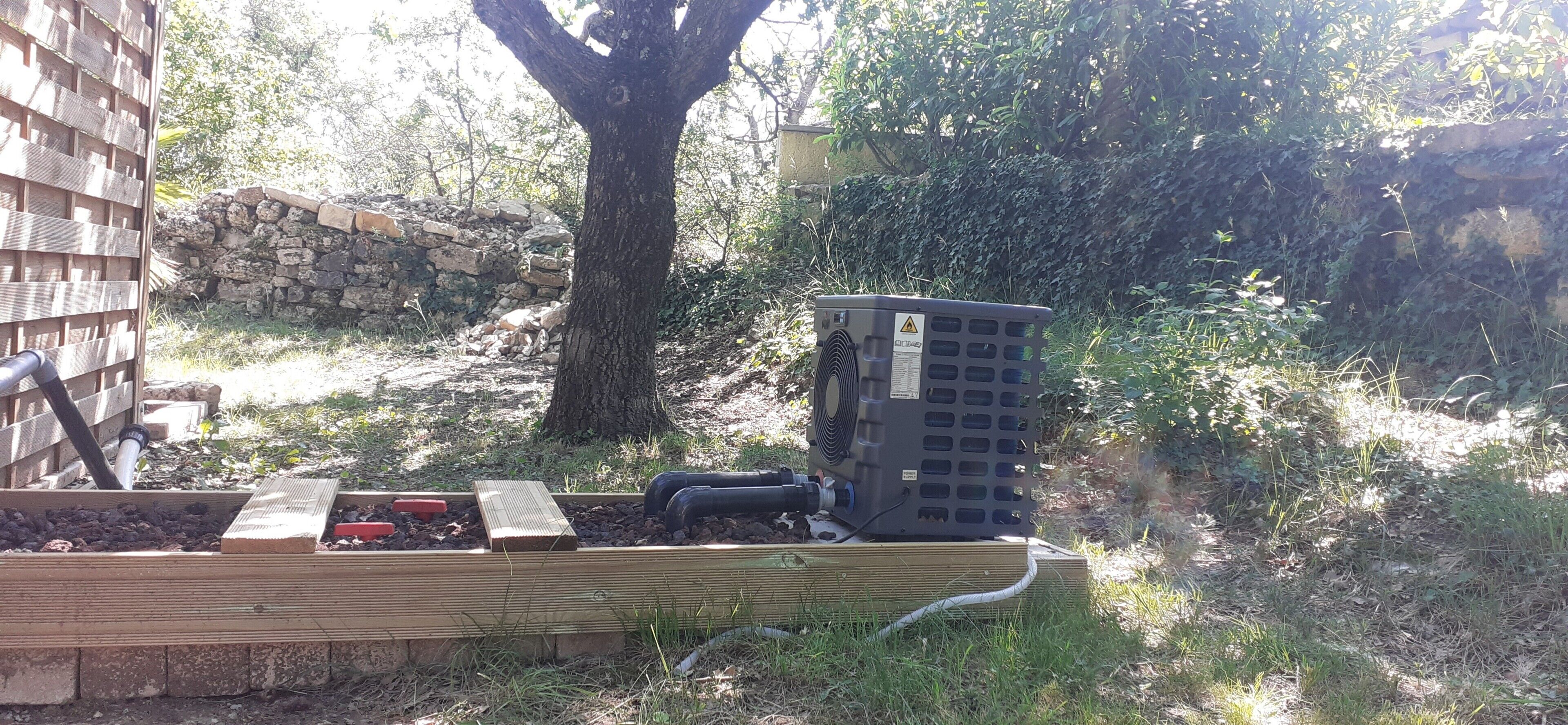 Zona exterior amb un arbre, una paret de pedra i una caixa elèctrica negra.