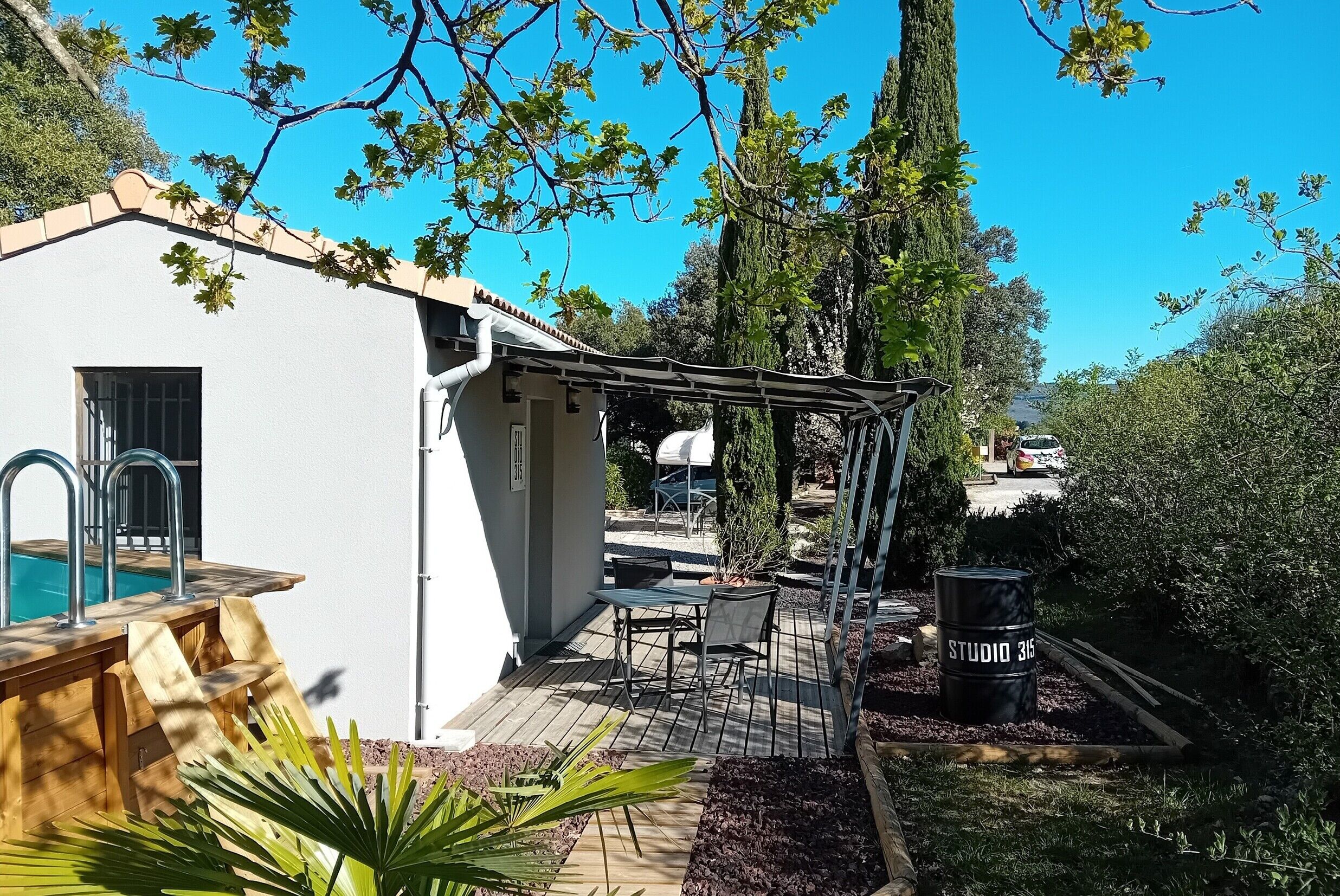 A white building with a pool, outdoor seating, and a pergola.