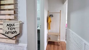 Een gang met houten vloer, een kledingroede met kleding en een bordje met de tekst 'AQUI TEM AMOT'.