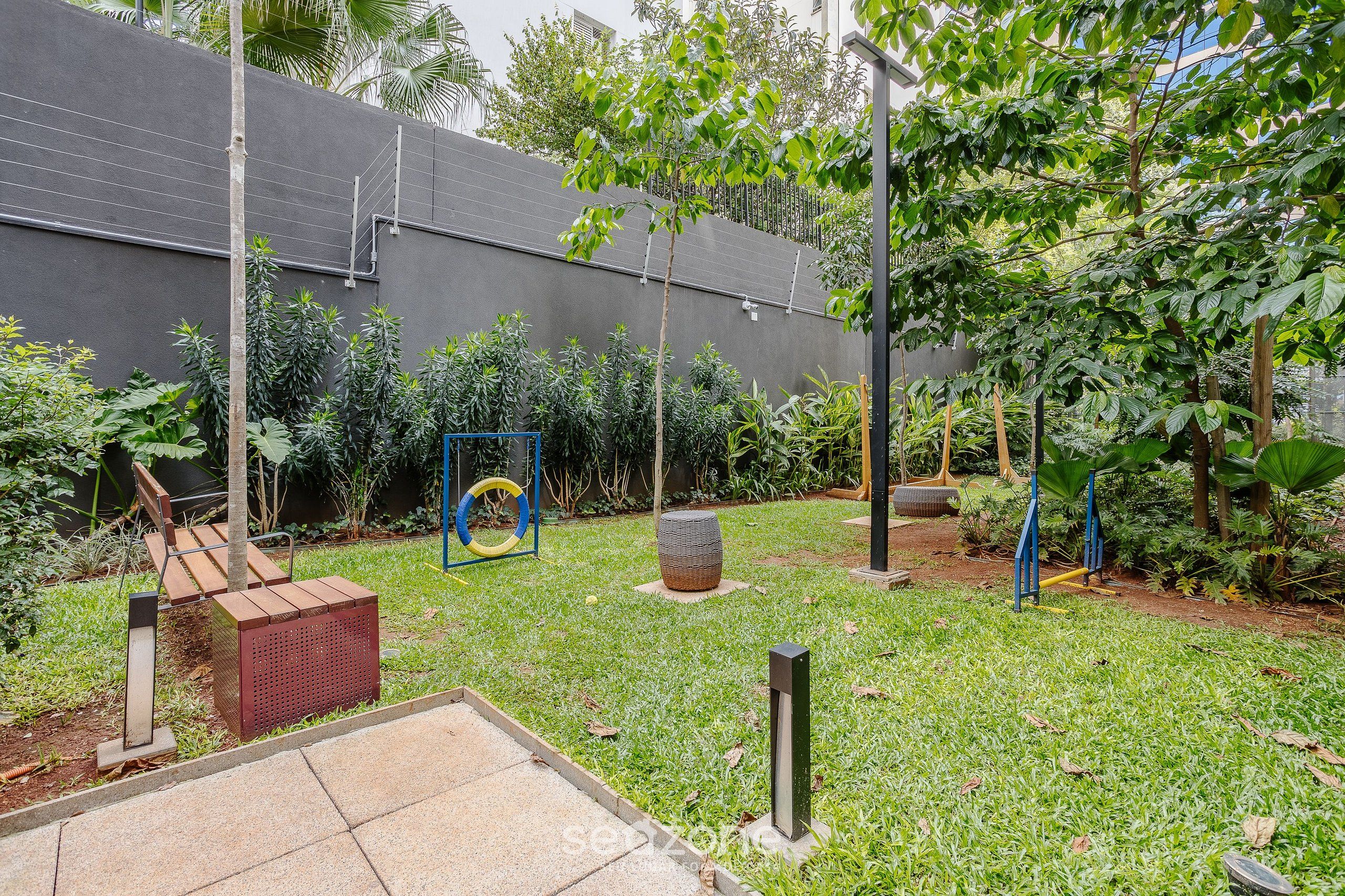 Een tuin met een betonnen muur, metalen constructies en diverse planten.