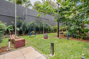 Un jardín con muro de concreto, estructuras metálicas y diversas plantas.