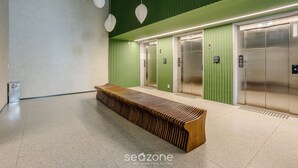 A modern elevator area with green walls, a wooden bench, and two elevators. - Your Urban Retreat Near the Subway - Iby1613 (São Paulo)