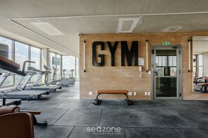 A gym with treadmills, a bench, and a large 'GYM' sign on the wall.