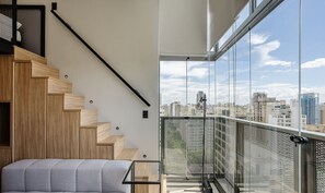 A modern apartment with a wooden staircase, a balcony with a metal railing, and a city view. - Your Urban Retreat Near the Subway - Iby1613 (São Paulo)