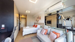 Une chambre d’hôtel moderne équipée de deux lits, d’un canapé, d’une télévision, d’un système de climatisation et d’un bureau avec un ordinateur.