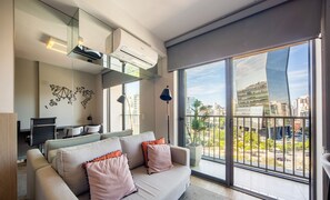 Een moderne woonkamer met een bank, een bureau en een groot raam met uitzicht op de stad.