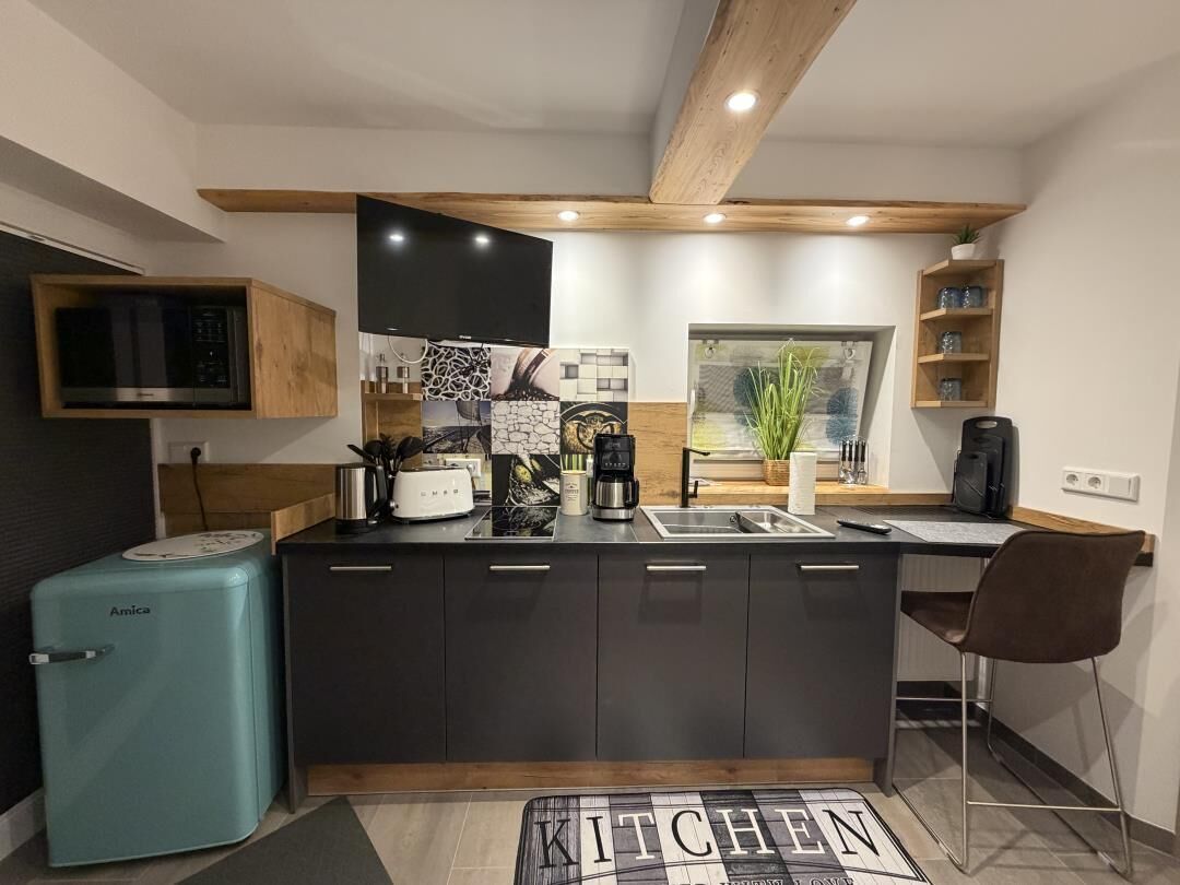 Une cuisine moderne dotée d’un îlot central, d’appareils électroménagers intégrés et d’un plafond en bois.