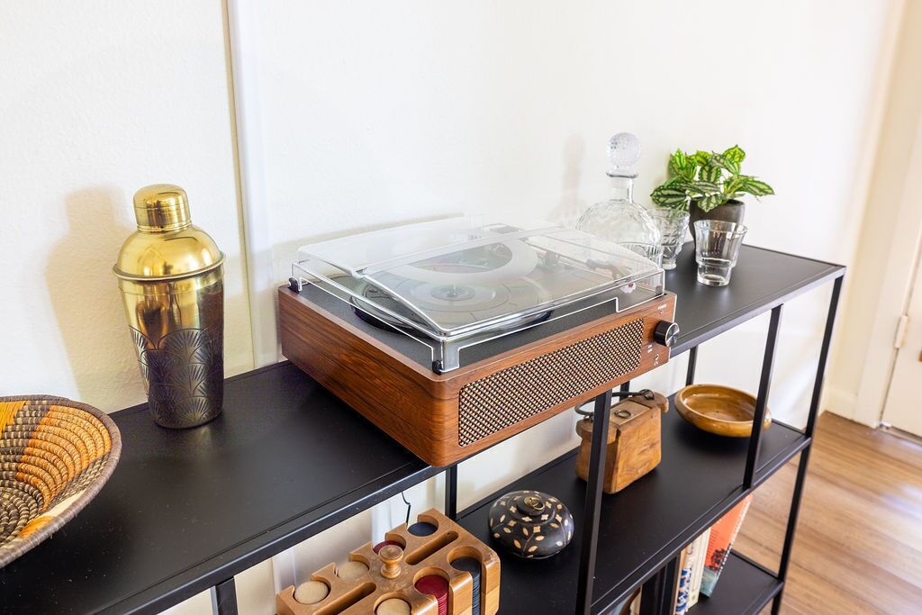 A wooden shelf with a vintage radio, a glass container, a small plant, and decorative items.