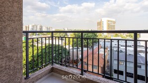 Een balkon met uitzicht op omliggende gebouwen en groen.