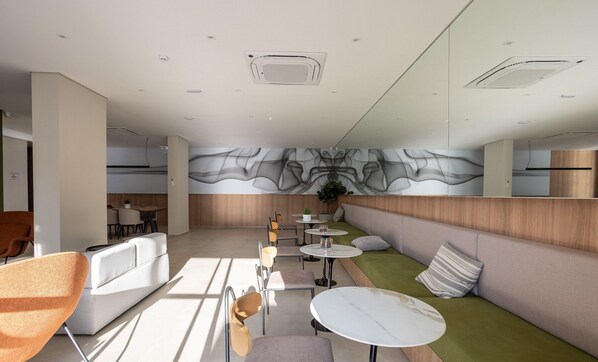 Un intérieur moderne comprenant un espace salon, des tables et une grande fresque murale abstraite.