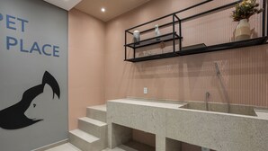 Een moderne badkamer met een granieten wastafel, een wand met dierenmotieven en een metalen plank met decoratieve voorwerpen.