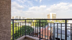 A balcony with a view of surrounding buildings and greenery.