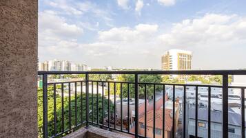 Uma varanda com vista para edifícios e vegetação ao redor.