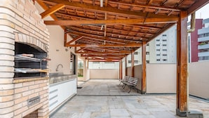 An outdoor patio with a brick oven, stone flooring, and a wooden pergola structure. -  1 Bedroom Apartment with pool 600m from Moema/SP metro station NPZ093 (São Paulo)