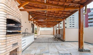 An outdoor patio with a brick oven, stone flooring, and a wooden pergola structure. -  1 Bedroom Apartment with pool 600m from Moema/SP metro station NPZ093 (São Paulo)