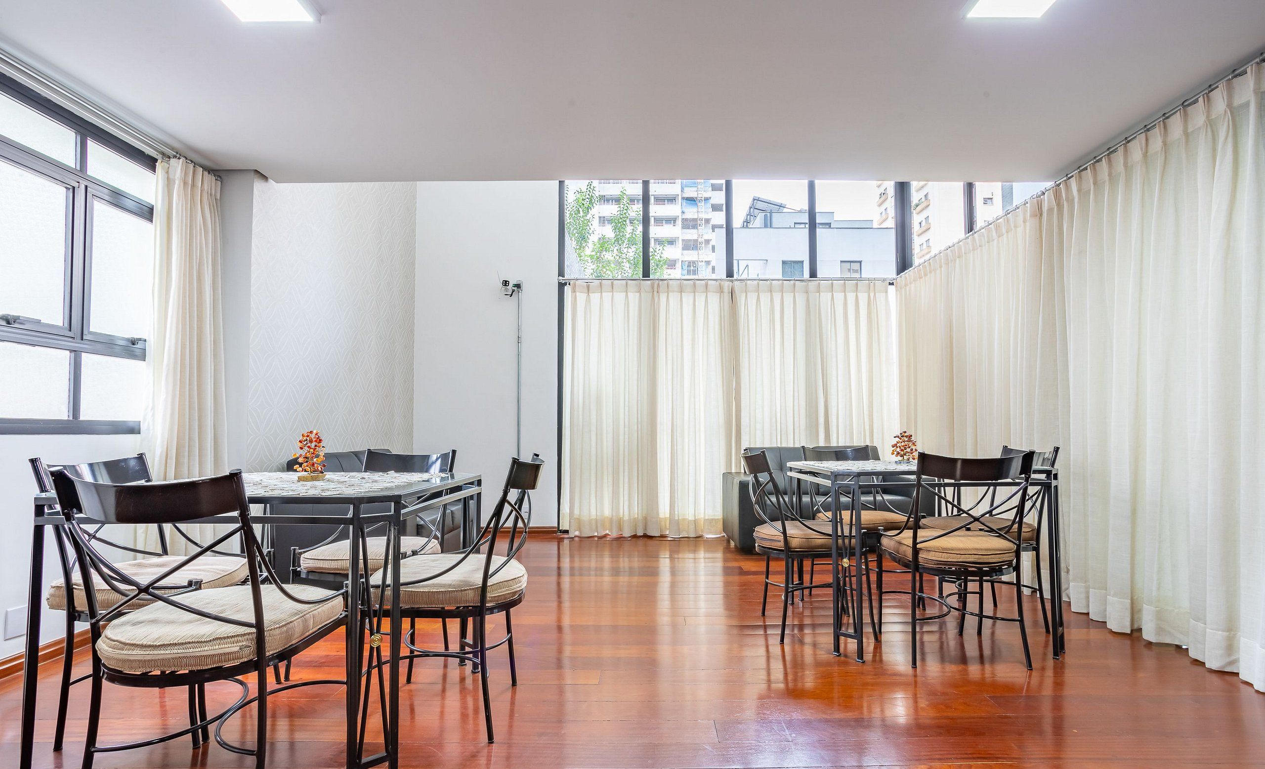 Uma sala de jantar com piso de madeira, cadeiras de metal preto e uma mesa.