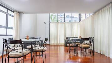Uma sala de jantar com piso de madeira, cadeiras de metal preto e uma mesa.