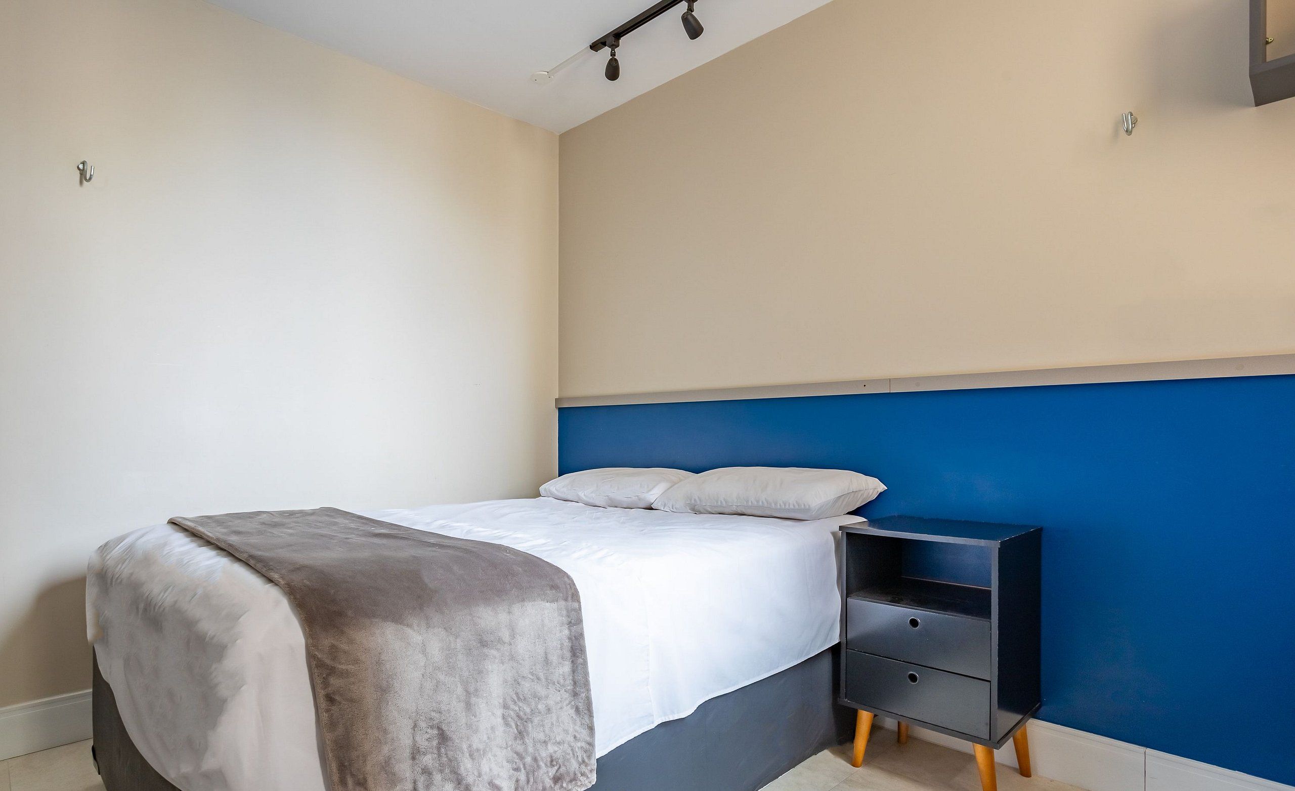 Quarto com cama, mesa de cabeceira e cabeceira.