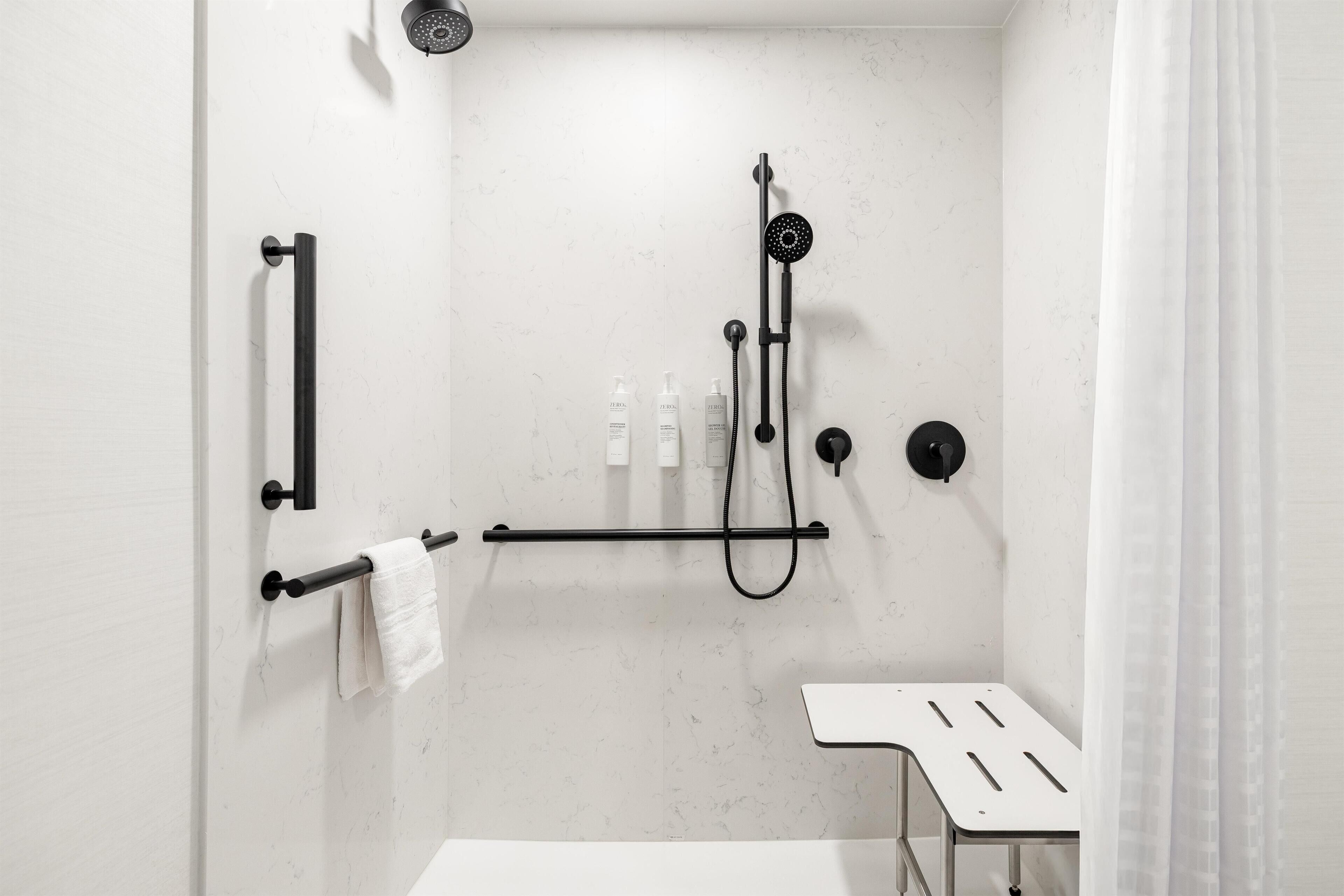 A modern bathroom with a shower, towel rack, and a small table.