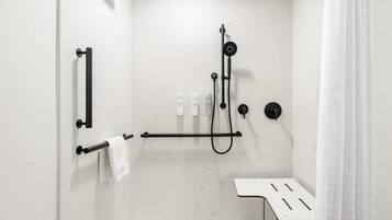 A modern bathroom with a shower, towel rack, and a small table.