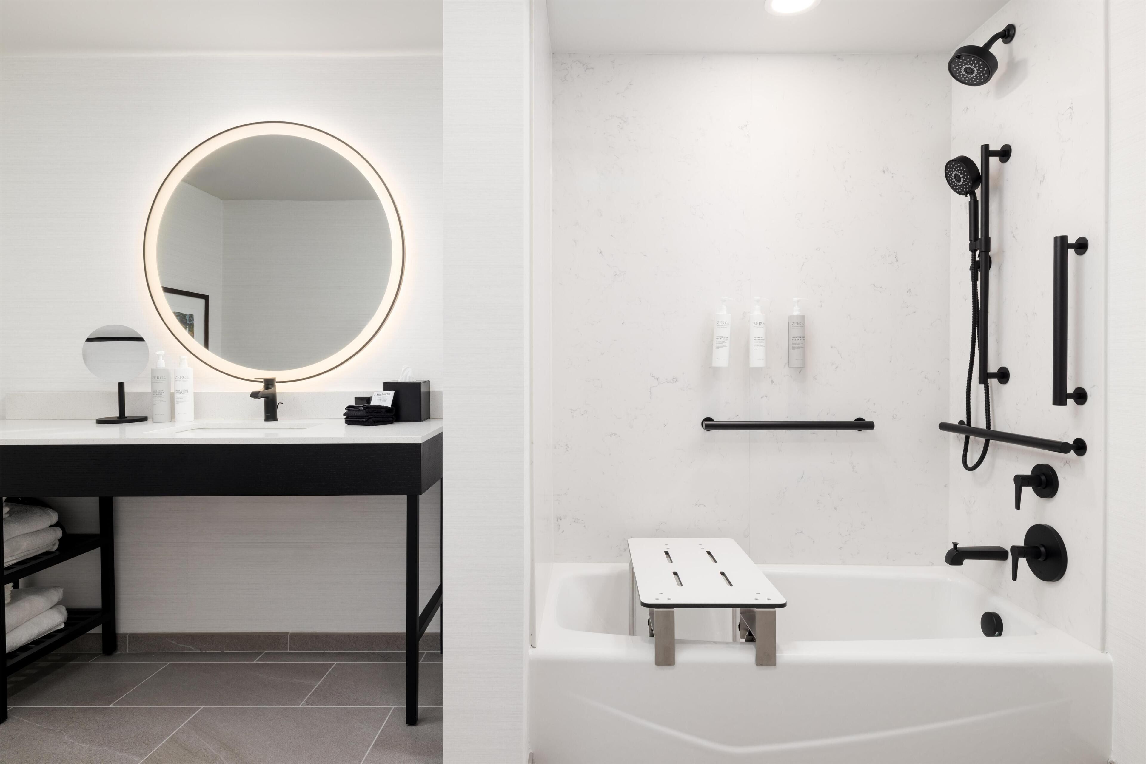 A modern bathroom with a round mirror, white sink, and black fixtures.