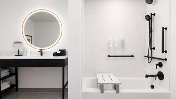 A modern bathroom with a round mirror, white sink, and black fixtures.