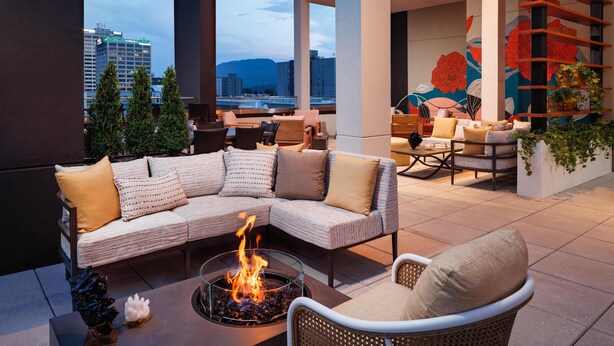 A modern outdoor seating area with a fire pit, cushioned seating, and a view of the cityscape. - Embassy Suites By Hilton Chattanooga Downtown (Chattanooga)