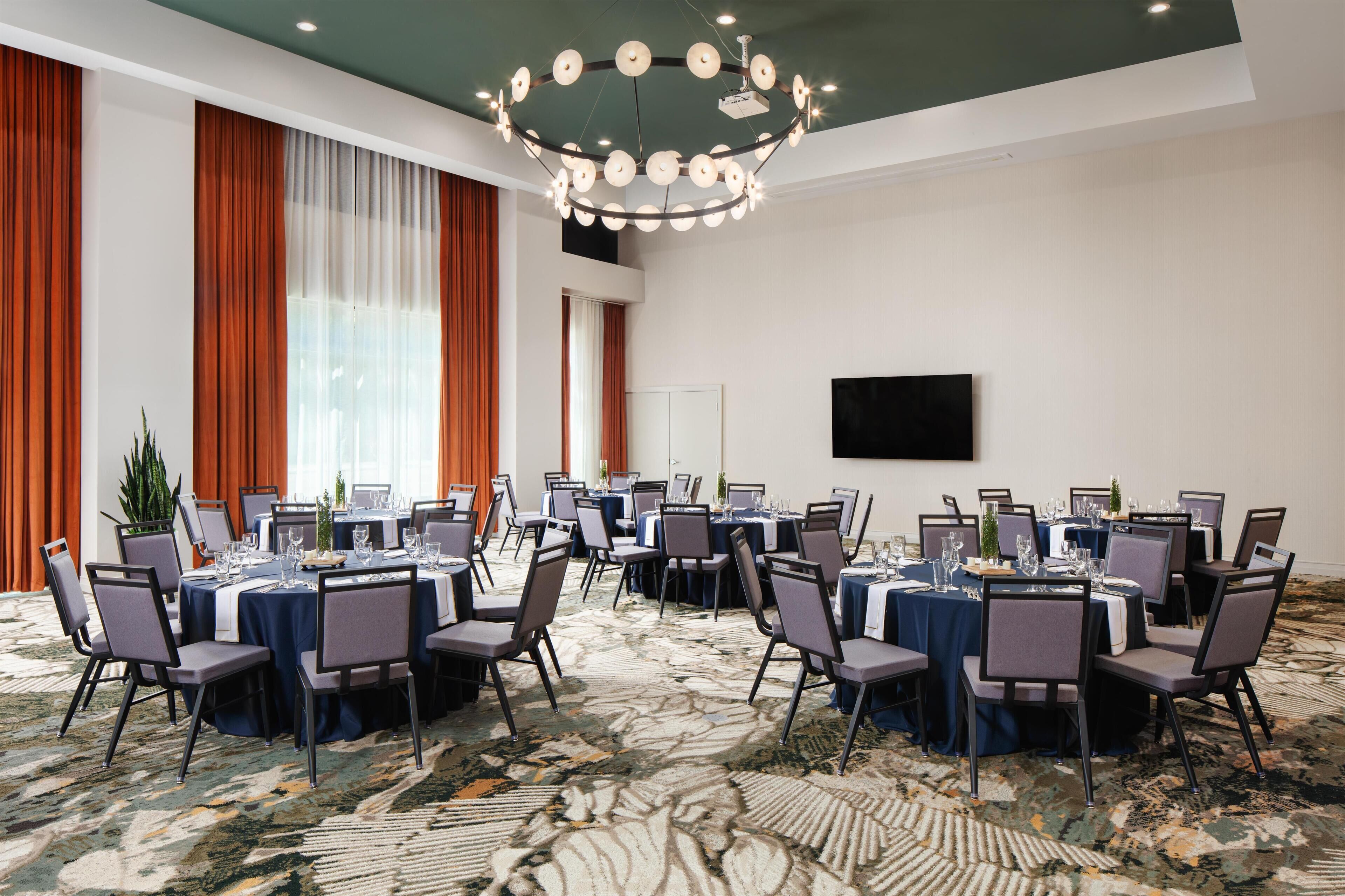 A conference room with round tables, chairs, and a large chandelier.