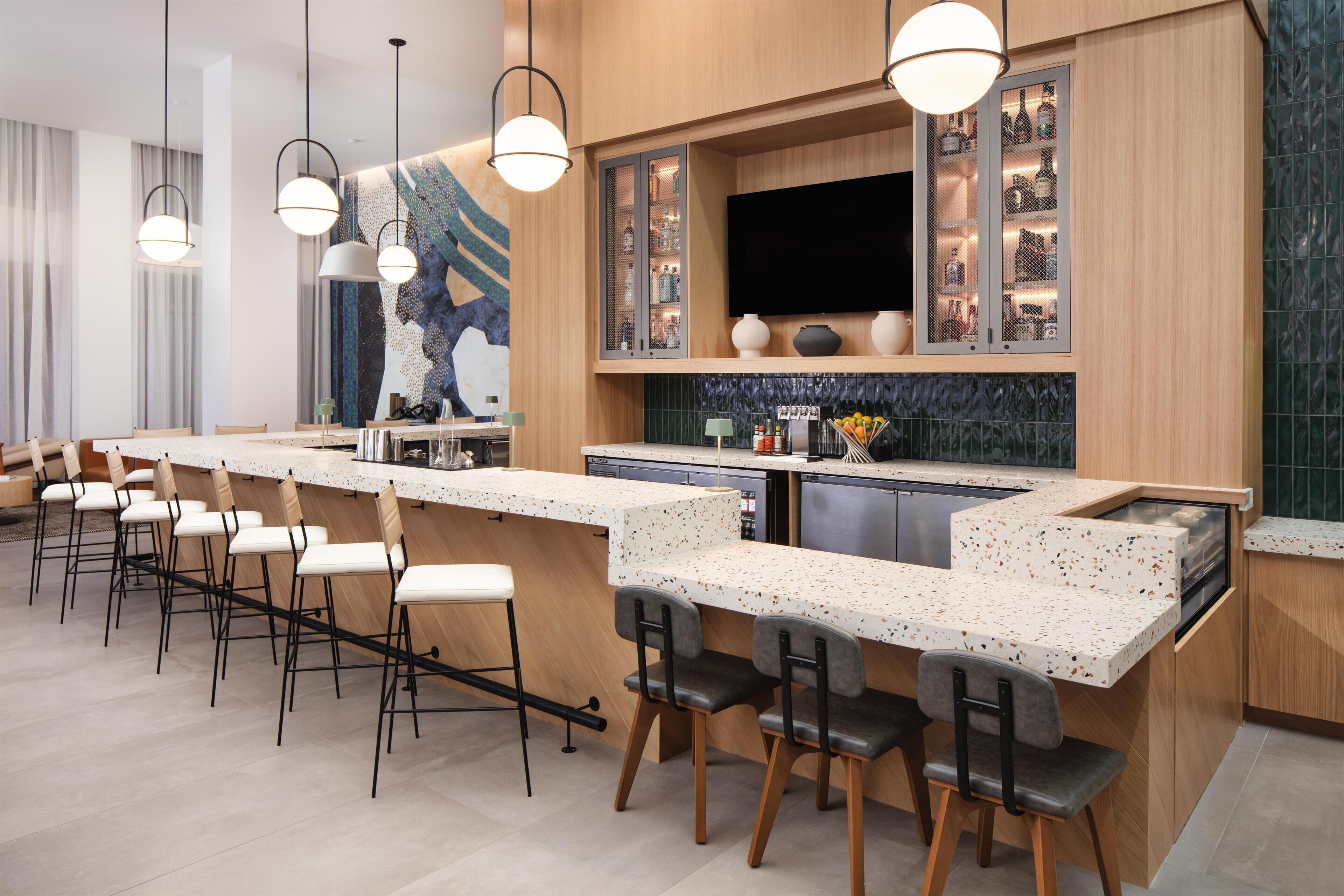 A modern kitchen with a long island counter, bar stools, and a built-in wine rack.