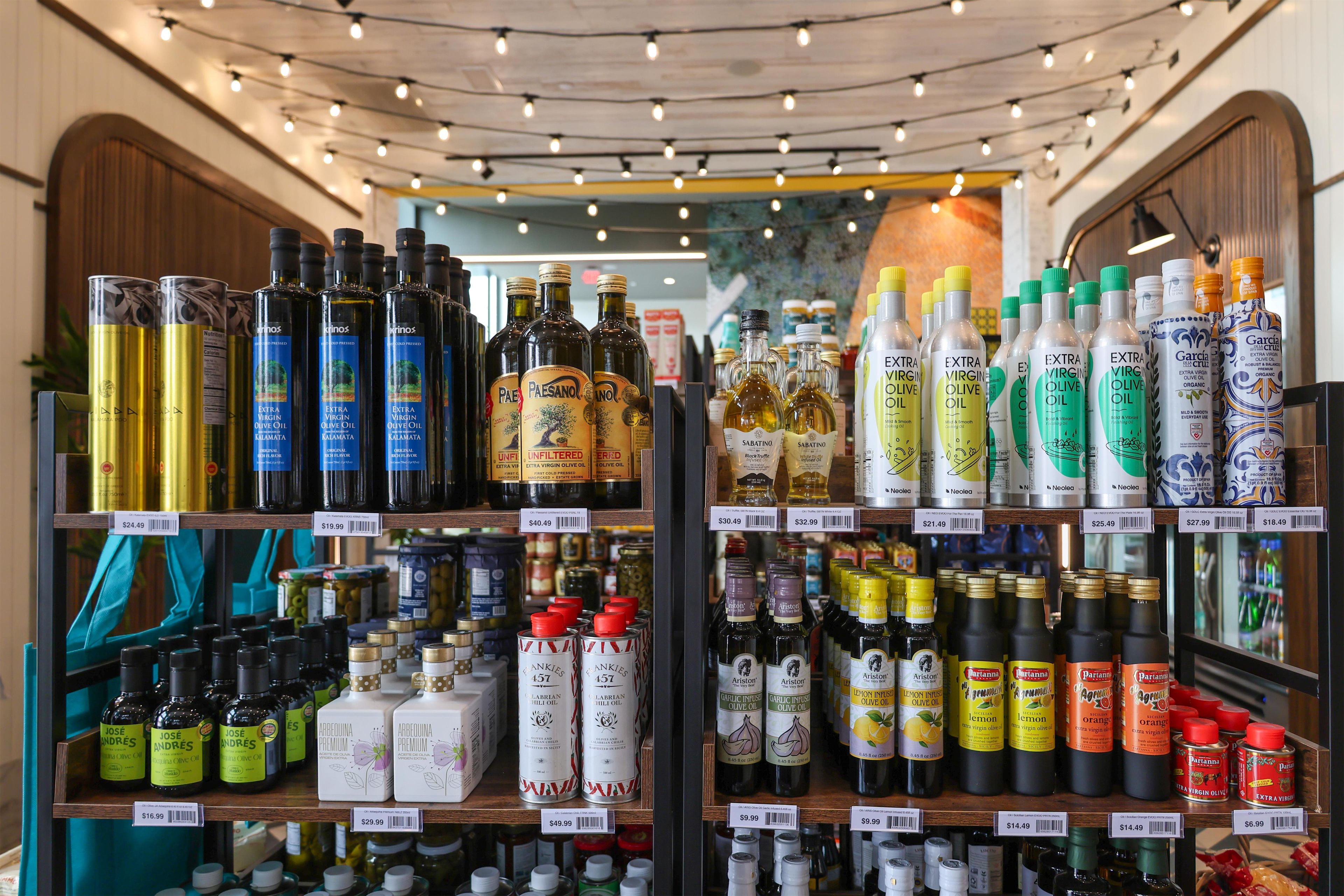 A variety of olive oil bottles on shelves in a store.