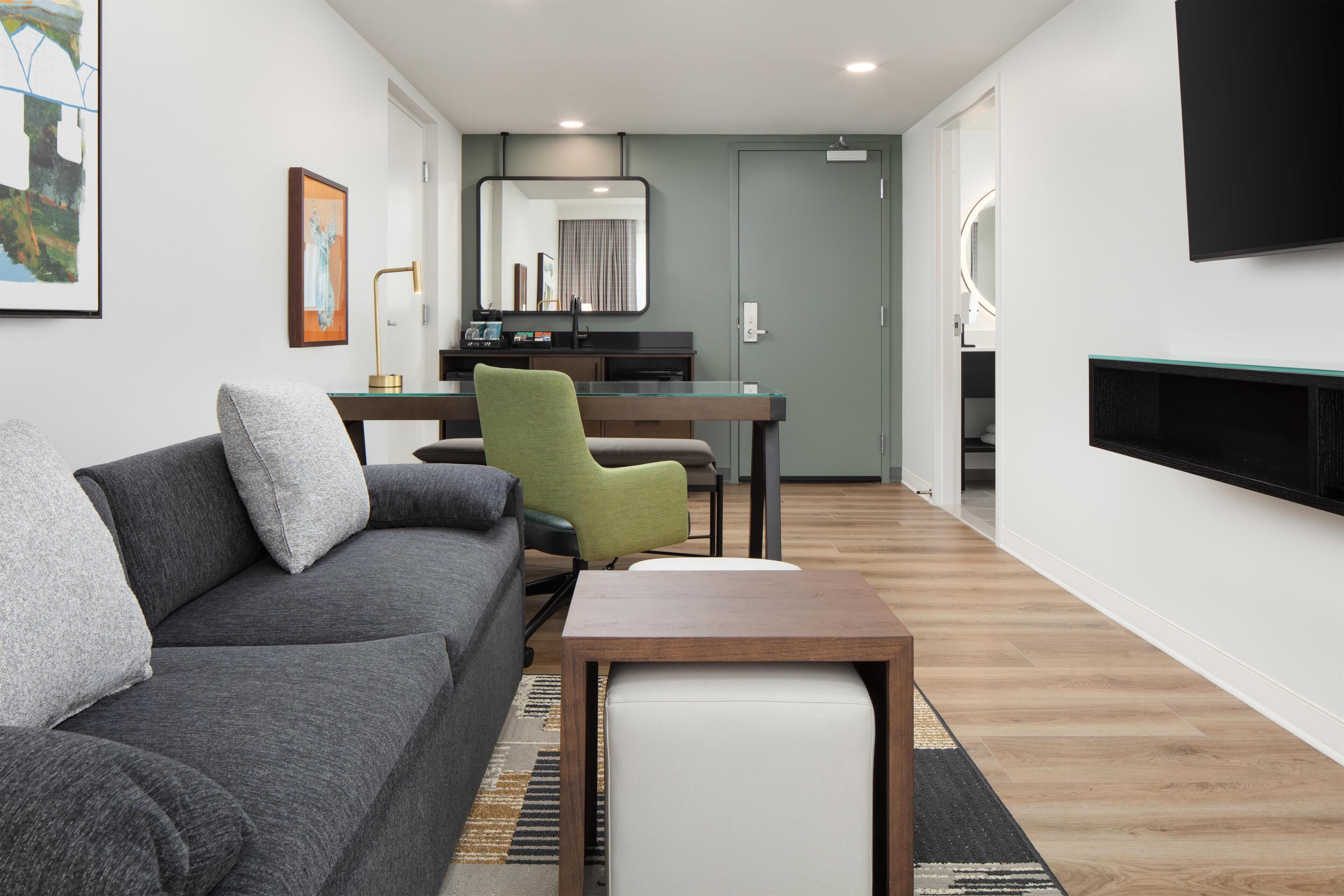 Un salon moderne avec un canapé gris, un fauteuil vert et une petite table en bois.