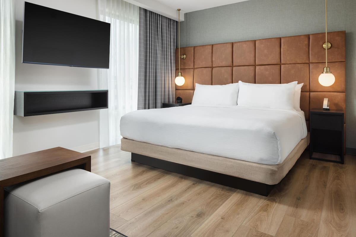 Cubrecamas, escritorio, tabla de planchar con plancha y ropa de cama