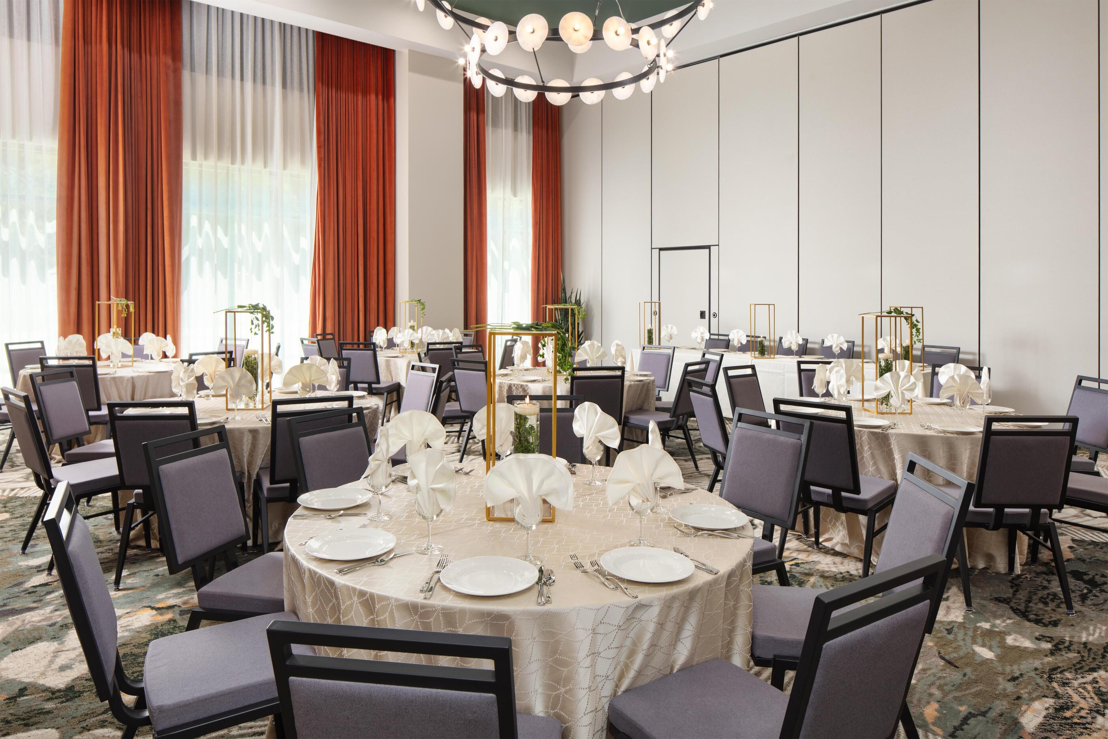 A conference room with round tables, chairs, and a chandelier.