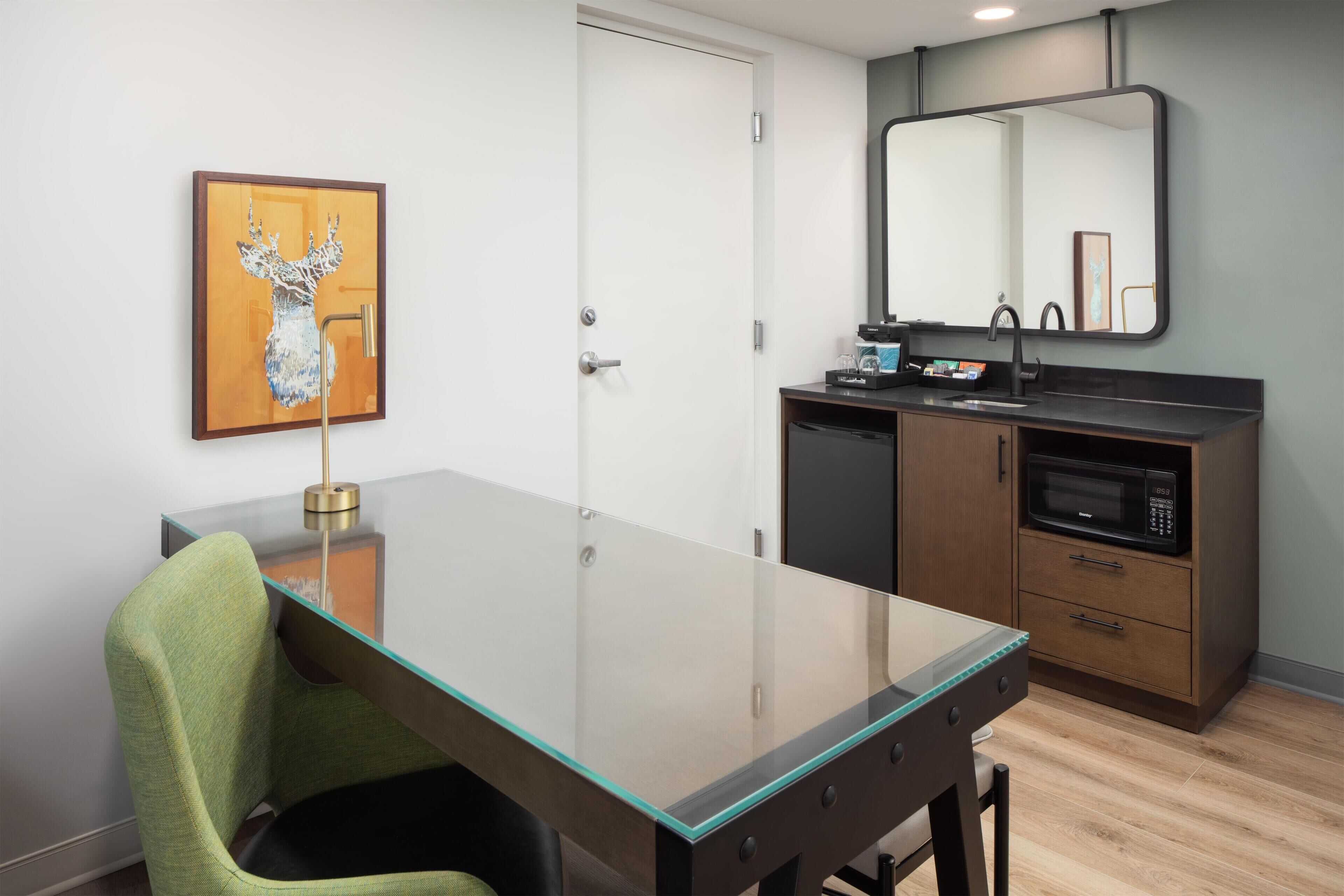 A modern kitchen with a glass-top table, a microwave, and a sink.