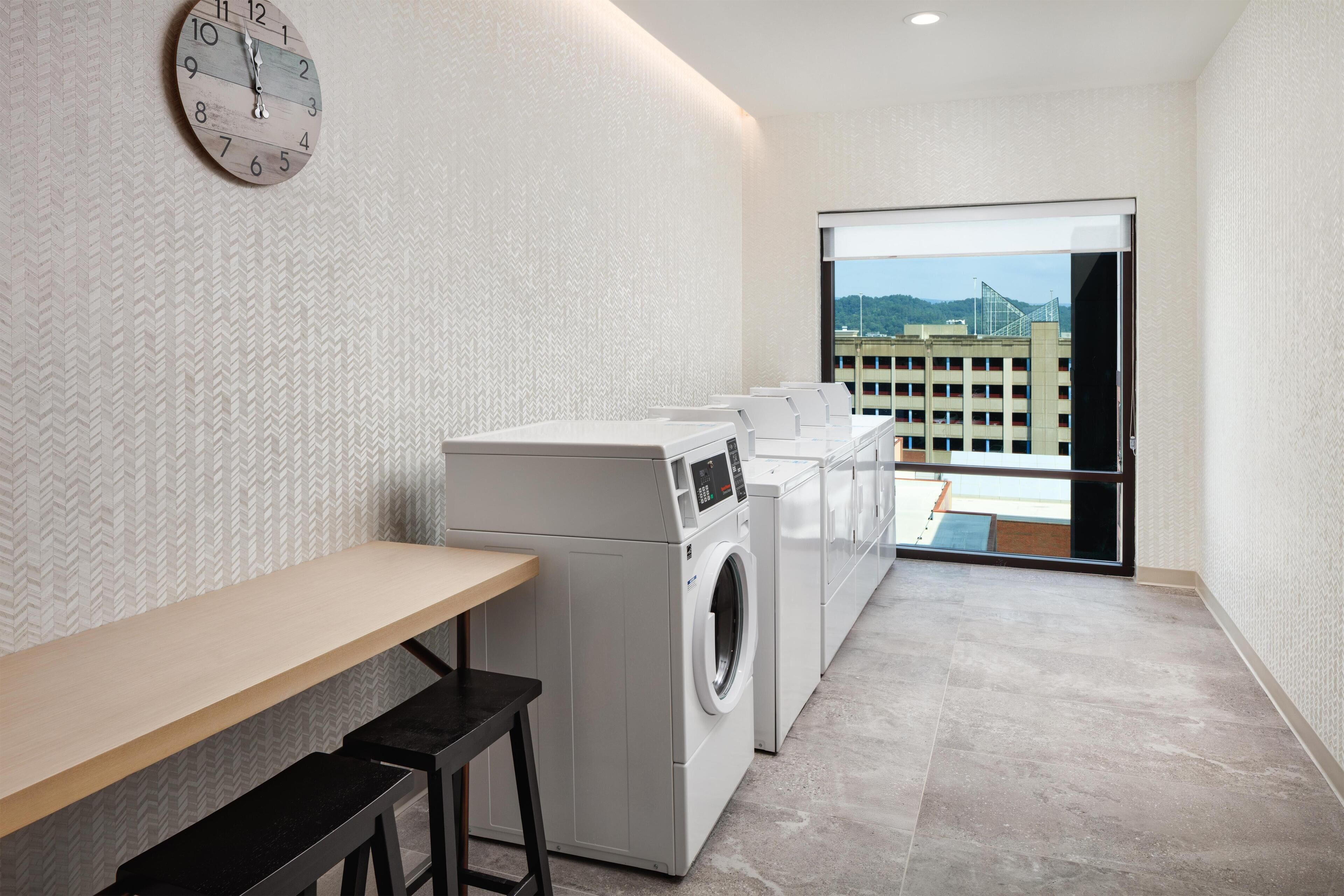 A laundry room with a washing machine, a dryer, and a clock on the wall.