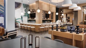 A modern hotel lobby with a bar area, seating arrangements, and a large dining table. - Embassy Suites By Hilton Chattanooga Downtown (Chattanooga)