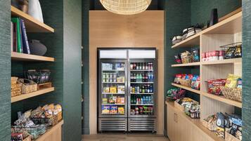 Een gang met een automaat voor snacks en planken vol met snacks en drankjes.