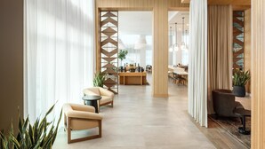 A modern hotel lobby with a central reception desk, seating area with sofas, and a dining space. - Embassy Suites By Hilton Chattanooga Downtown (Chattanooga)