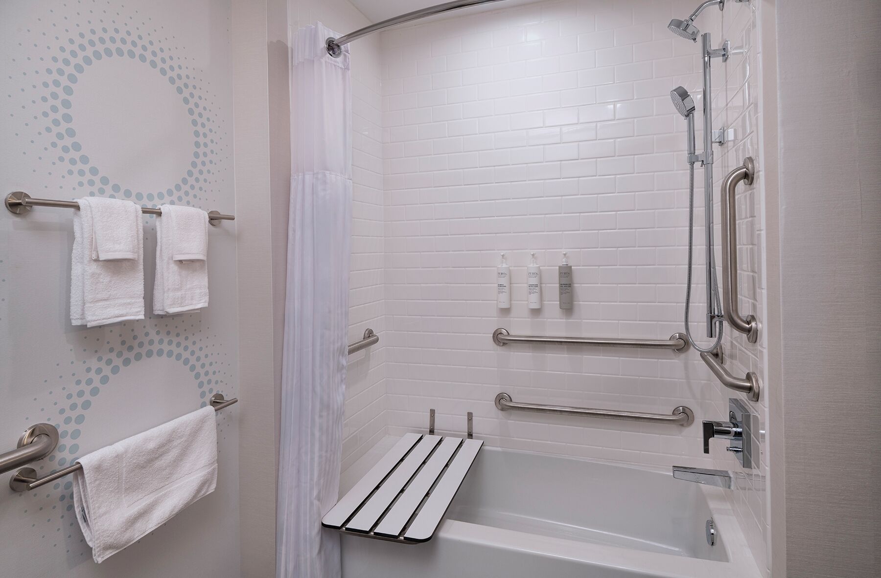 Un baño moderno con cabina de ducha, barras de apoyo y un perchero.