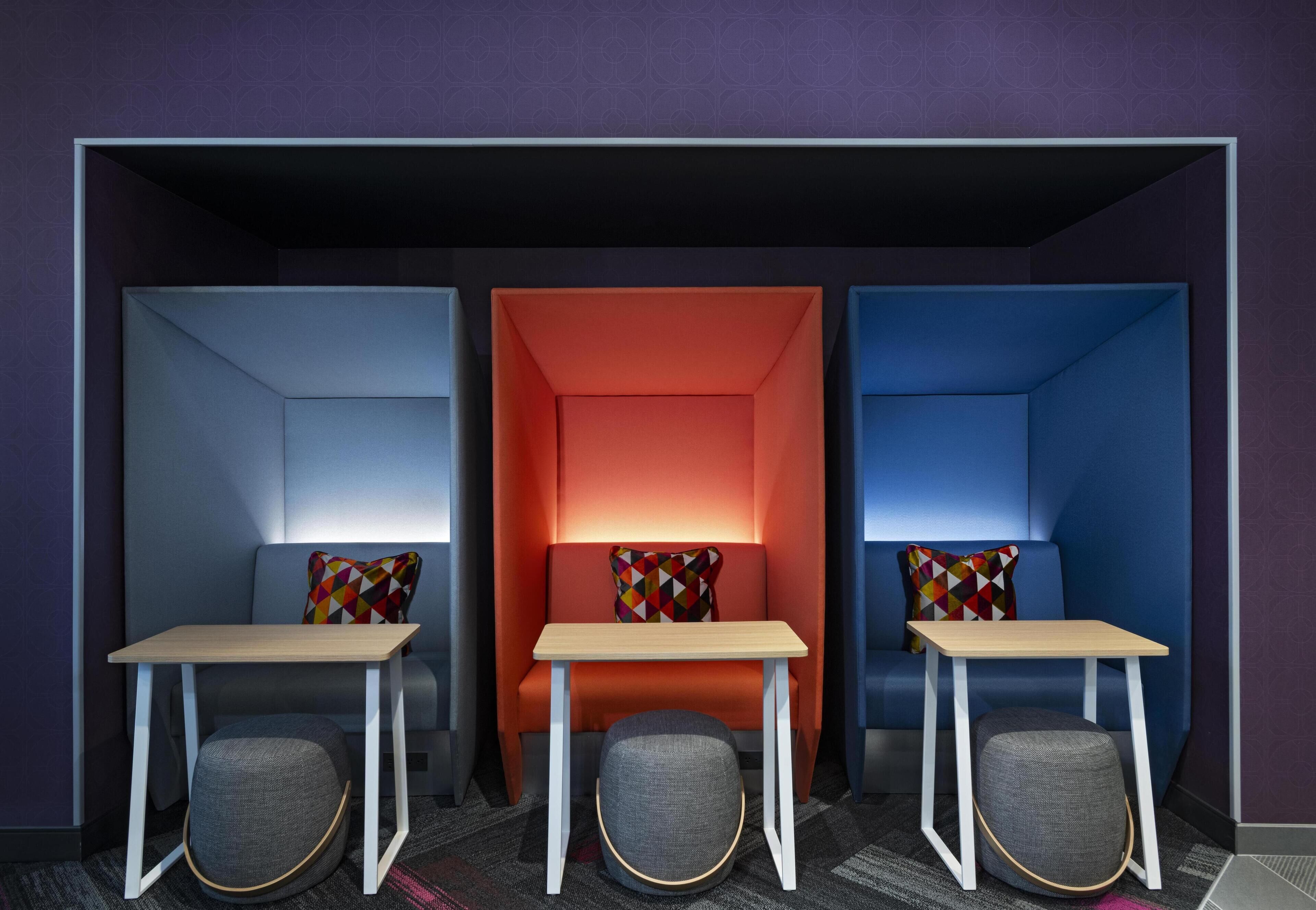 A modern room with three seating areas, each with a table and a chair.