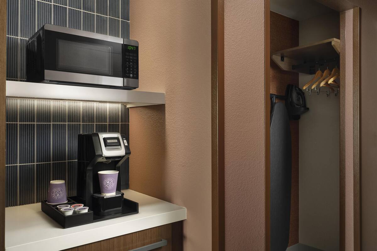 Une petite cuisine équipée d’un four à micro-ondes, d’une machine à café et d’un étendoir.