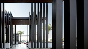 A modern architectural structure with vertical columns, a concrete pathway, and a view of palm trees and a distant building. - Hilton Garden Inn Merced (Merced)