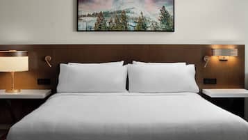 A hotel room with a large bed, two bedside tables with lamps, a wall-mounted painting, and a small table with a lamp.